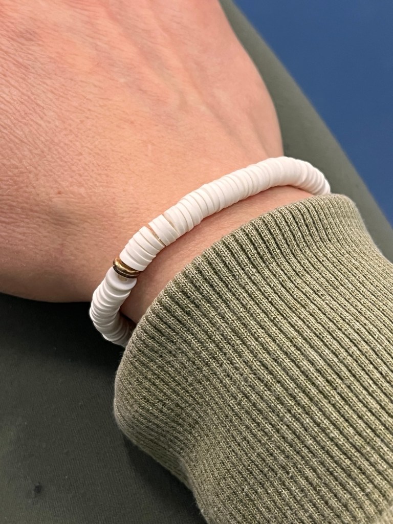bracelet with white beads, one grey bead and one gold bead